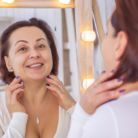 middle aged woman inspecting her skin in mirror